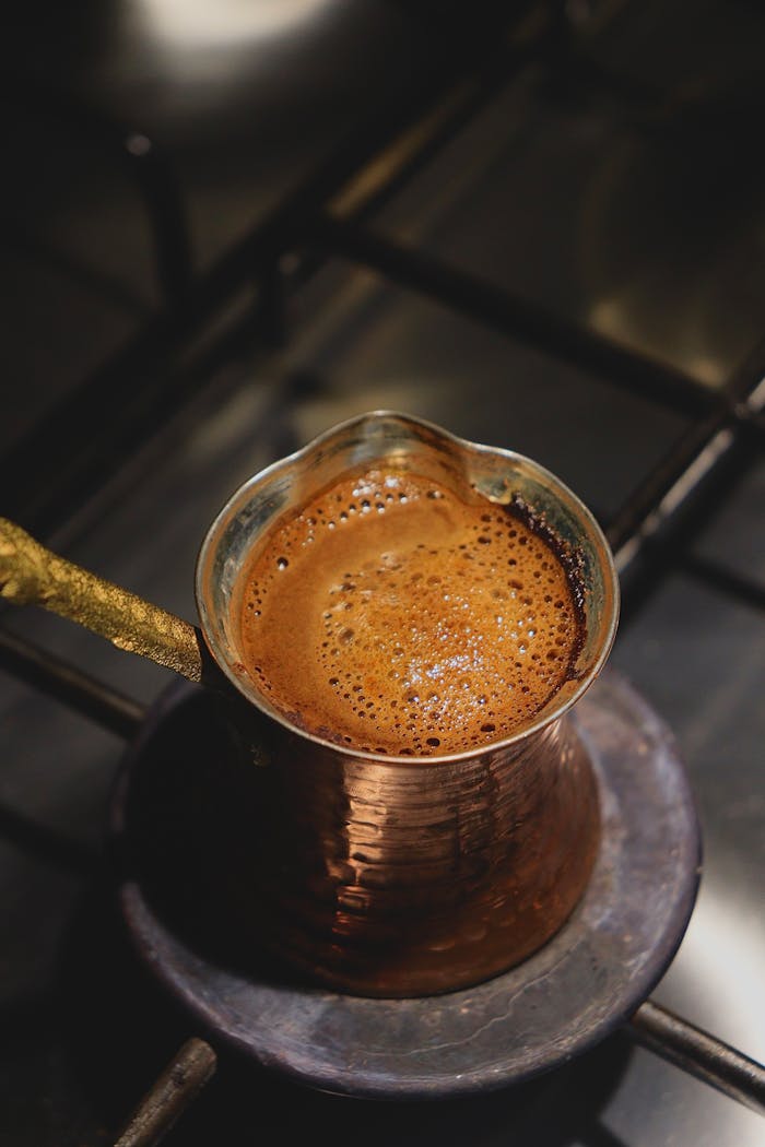 Close-up of bubbling Turkish coffee in a cezve on the stove. Rich aroma and golden foam.