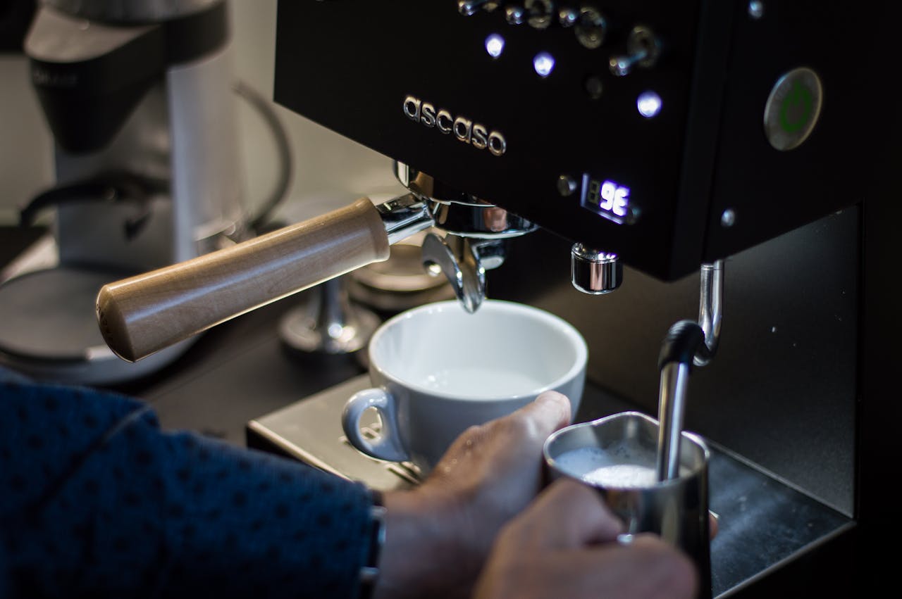 Close-up of a barista frothing milk and preparing espresso with a high-end coffee machine.